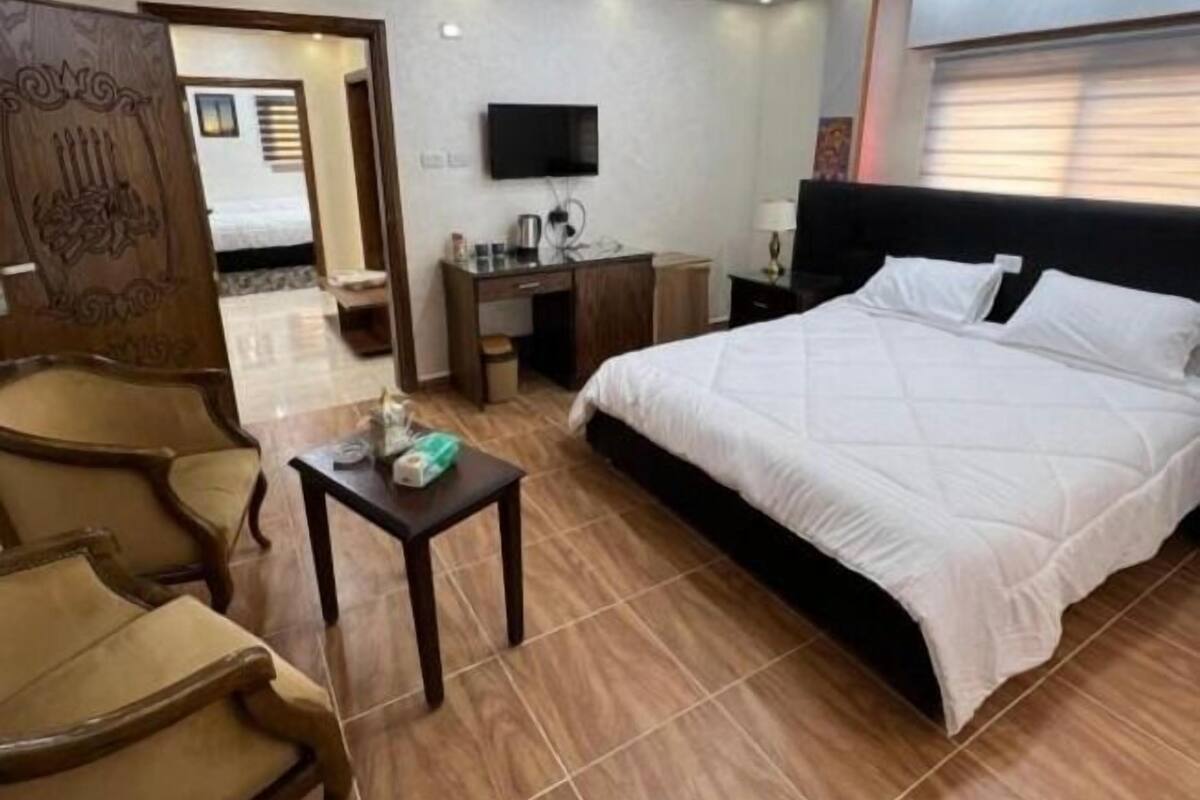 Una camera d'albergo con un letto, una scrivania, una sedia, un televisore e un elemento decorativo a parete.