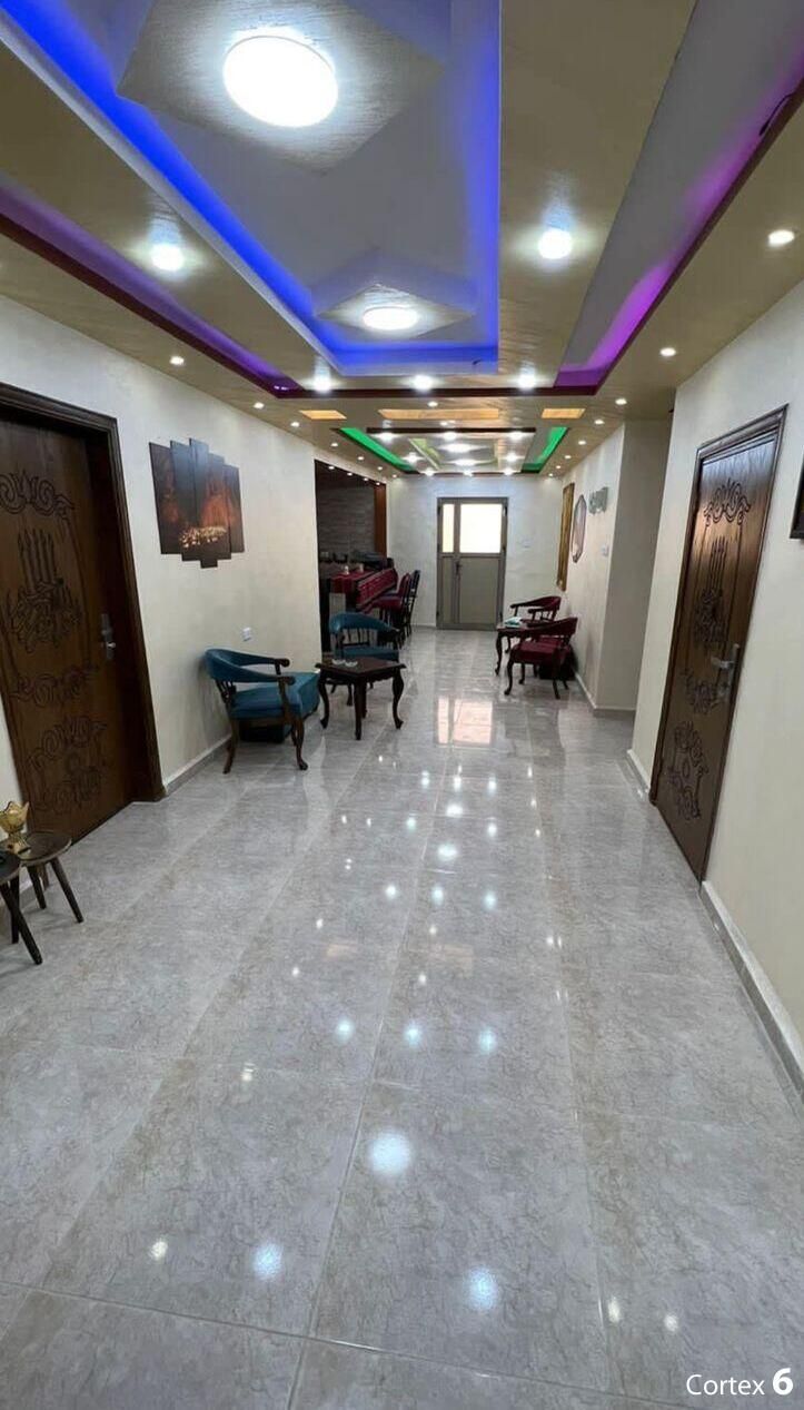 A hallway with a dining area, featuring a marble floor, wooden doors, and ceiling lights.