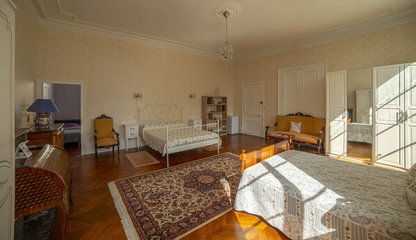 Une chambre spacieuse avec un grand lit, un canapé, un fauteuil, une table de chevet, une lampe et une bibliothèque.