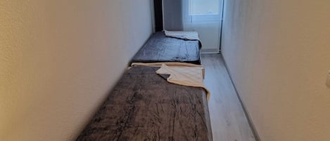 Un couloir étroit avec un lit au fond.