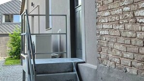 Ein modernes Gebäude mit Ziegelaußenwand, einer Treppe, die zu einer Tür führt, und einem Metallgeländer.