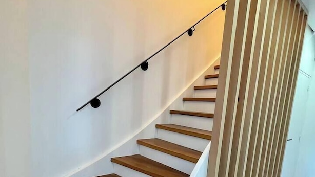 Eine Holztreppe mit weißen Geländern und einer Leuchte darüber.