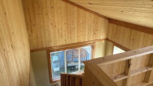 Una habitación con techos altos, paneles de madera y un amplio ventanal.