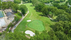 Ein Luftbild eines Golfplatzes mit Clubhaus, Schwimmbad und umliegenden bewaldeten Gebieten.