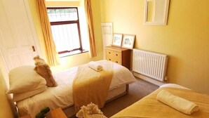 A hotel room with two beds, a dresser, a radiator, and a window with curtains. - Rustic 2bedroom Cottage With Garden in Sennybridge (Brecon)