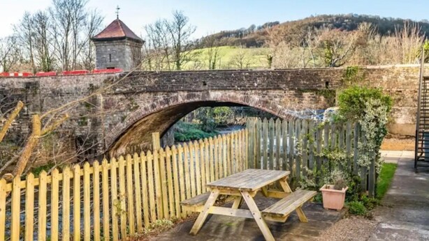 A stone bridge with a wooden picnic table and a fence. - Rustic 2bedroom Cottage With Garden in Sennybridge (Brecon)