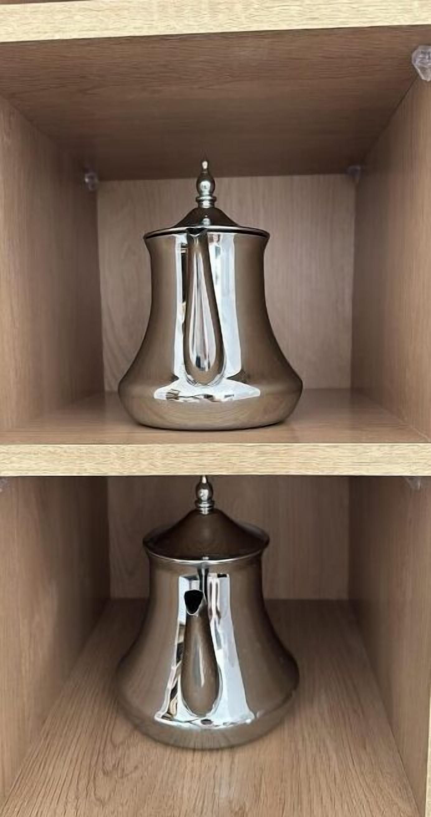 Two metallic, reflective vases on wooden shelves.