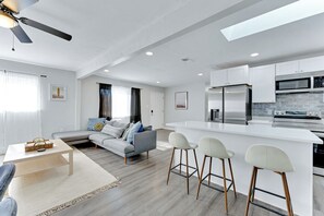 A modern kitchen with white cabinets, a stainless steel refrigerator, and a microwave. - Virginia Beach 3BR Home + Furnished 30+ Night Stay (Virginia Beach)