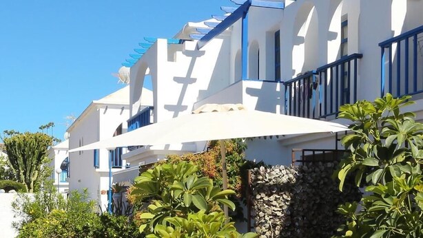 Una hilera de edificios blancos con detalles azules, probablemente parte de un hotel o complejo turístico.