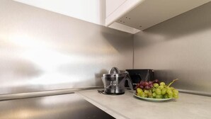 Una cocina con un exprimidor de frutas, un cuenco de uvas y una encimera negra.
