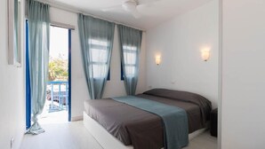 Un dormitorio con cama, ventilador de techo y vistas al exterior.