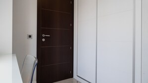 Una habitación con una puerta de madera oscura, una pared blanca y una mesa de vidrio con una silla.