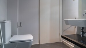 Un baño moderno con inodoro, lavamanos y espejo.