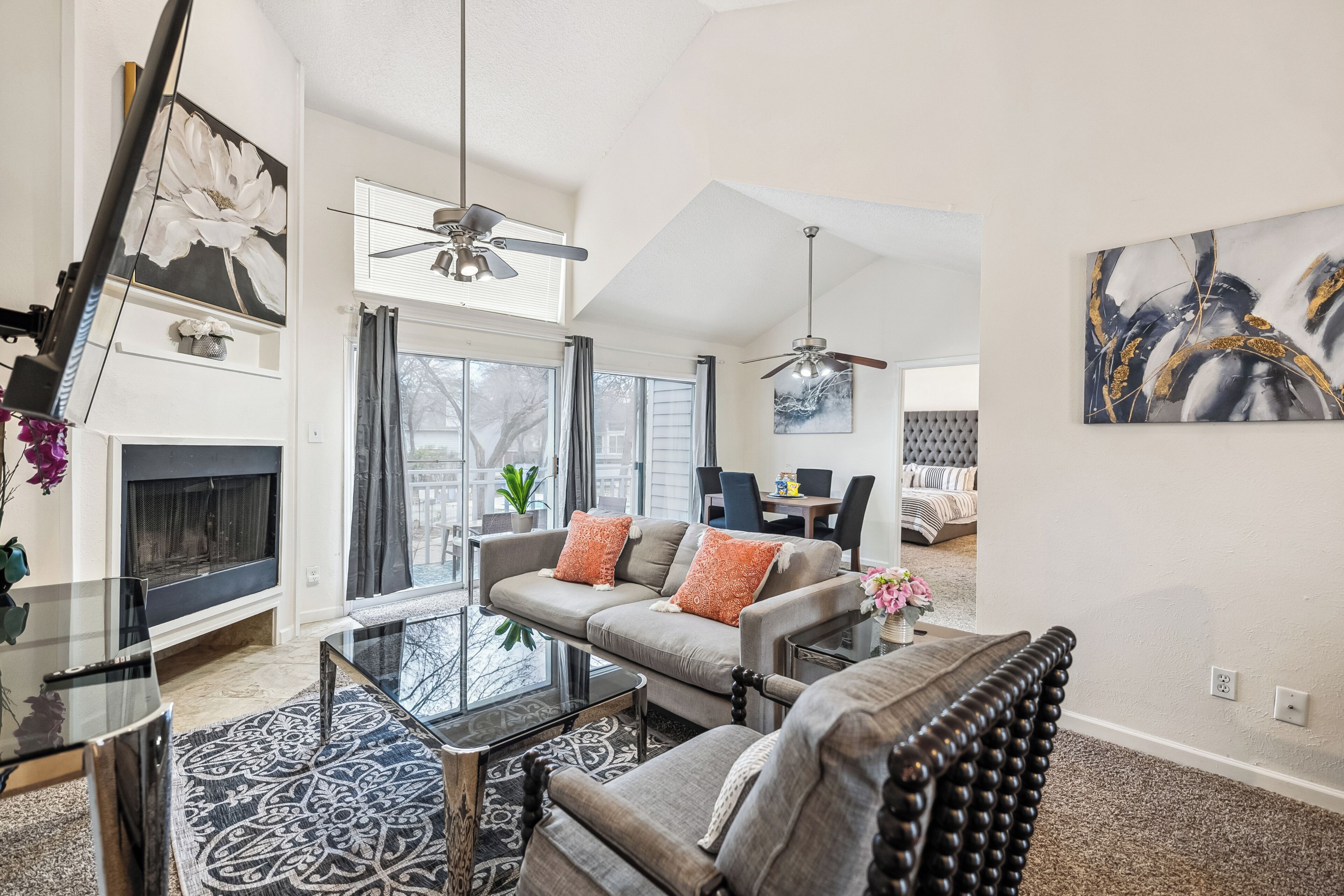 A spacious living room with a fireplace, a dining area, and a bedroom with a tufted headboard.