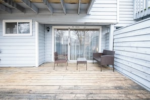 A covered patio area with a sliding glass door, two wicker chairs, and a small table.