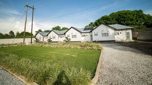 Une rangée de maisons blanches dotées de panneaux solaires, une allée en gravier et une zone herbeuse avec des plantes.