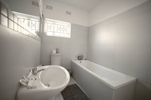 A bathroom with a white sink, a bathtub, and a toilet. - 24/7 Solar Power| Wi-Fi| 5 mins to East Park Mall Safe (Lusaka)