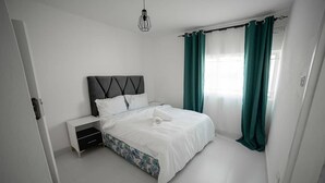 Une chambre à coucher moderne avec un lit, une table de chevet et un luminaire suspendu.