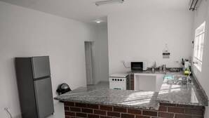 Une cuisine de taille réduite, dotée d’un plan de travail en granit, d’un réfrigérateur, d’une cuisinière et d’un four à micro-ondes.