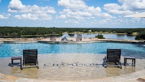 A pool area with lounge chairs and a fountain, surrounded by a natural landscape.