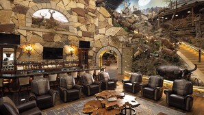 A lobby with stone walls, a bar area, leather seating, and a large mural of wildlife.