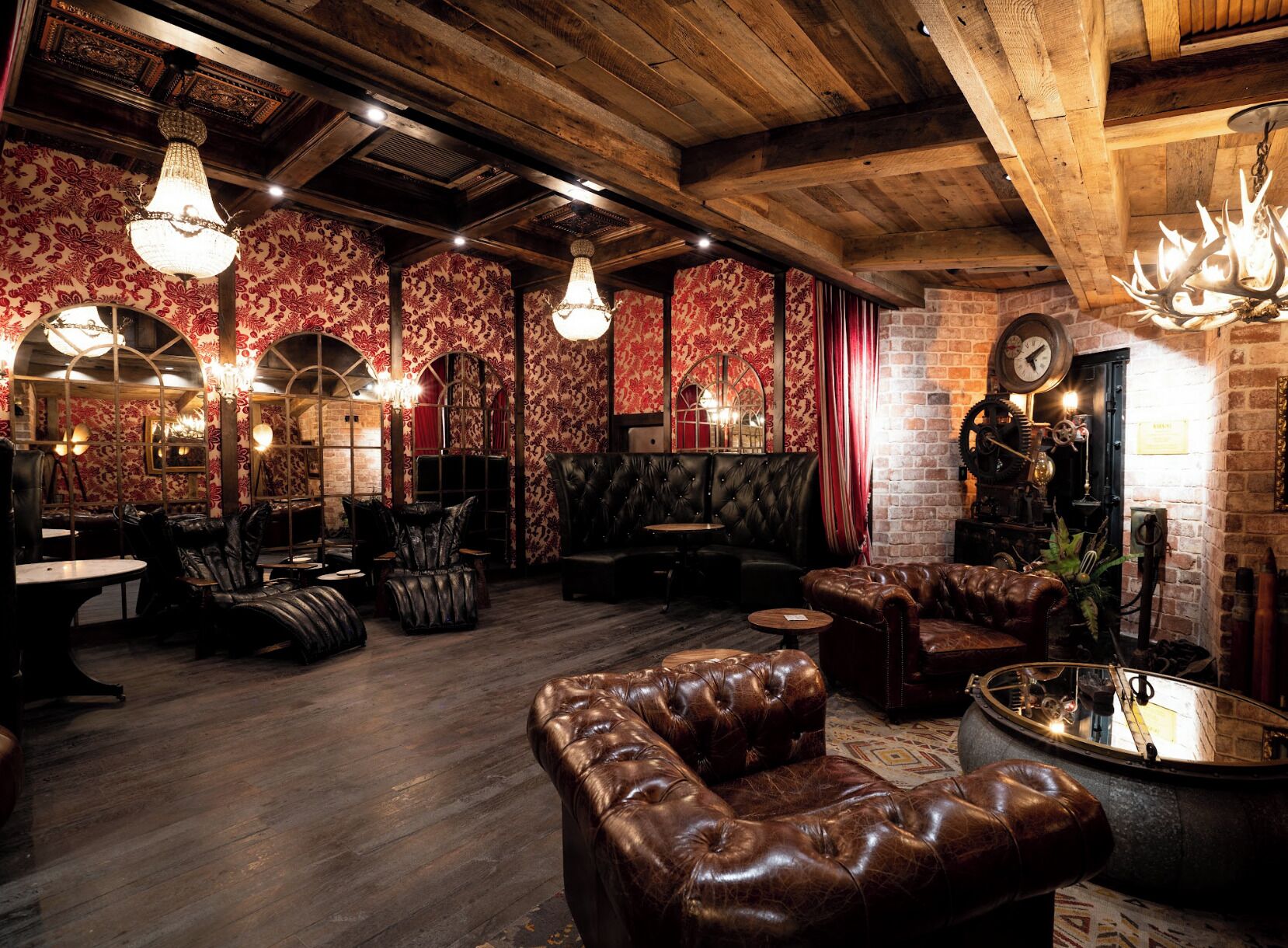 A rustic interior with leather seating, wooden beams, and patterned wallpaper.