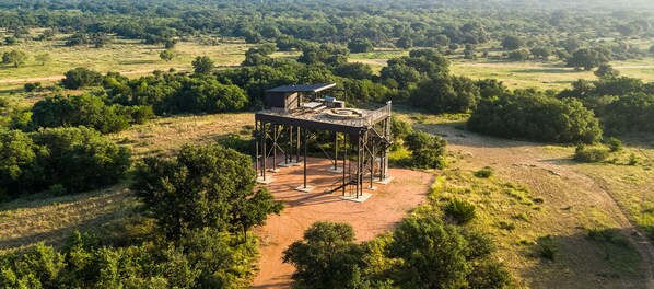 An elevated outdoor structure with a viewing platform, surrounded by a natural landscape.