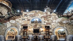 A stone-walled bar area with leather chairs and a large flat-screen TV.