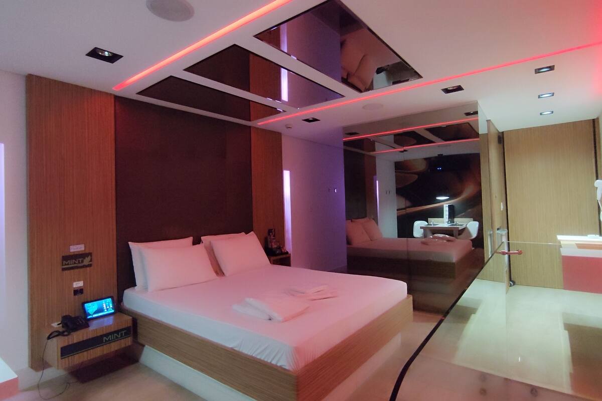 A modern hotel room with a large bed, a desk, and a seating area.