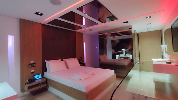 A modern hotel room with a large bed, a desk, and a seating area. - Mint Motel (Guarulhos)