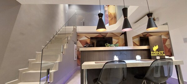Una cocina moderna con una isla central, una escalera e iluminación colgante.
