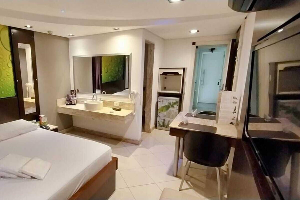 Una habitación de hotel moderna con una cama grande, un baño con tocador y un televisor.