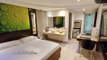 A modern hotel room with a large bed, a bathroom with a vanity, and a television.