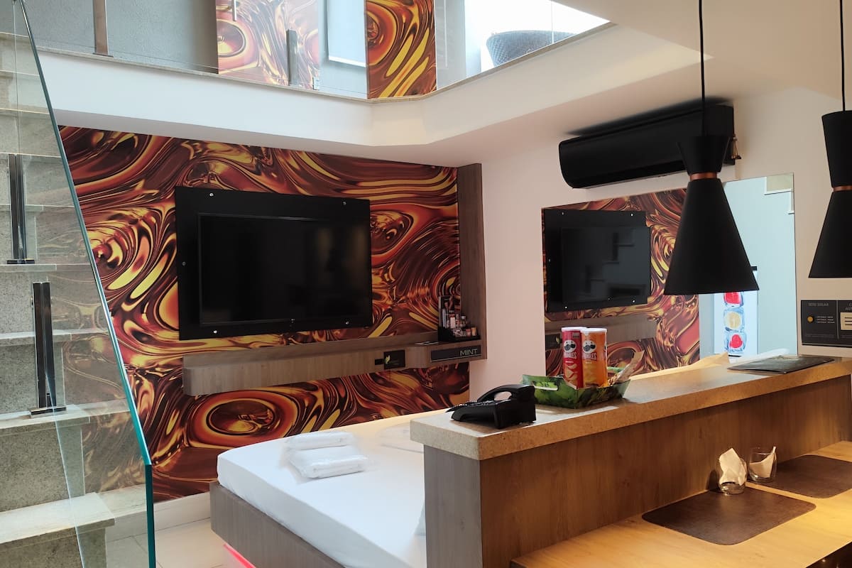 A modern kitchen with a marble backsplash, a built-in TV, and pendant lighting.