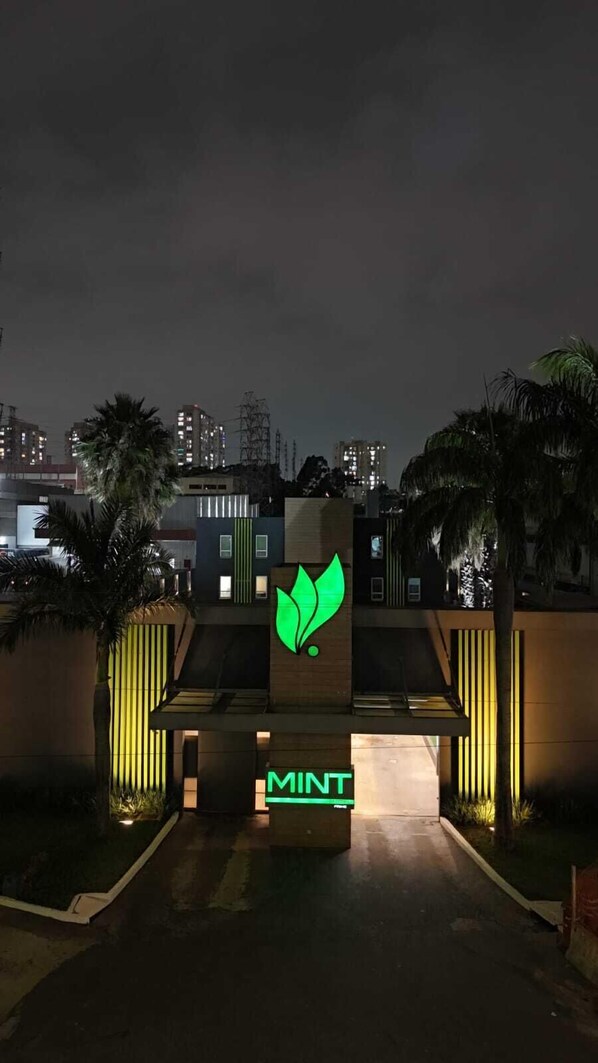 Un edificio moderno con un logotipo de hoja verde y la palabra “MINT” iluminada por la noche.