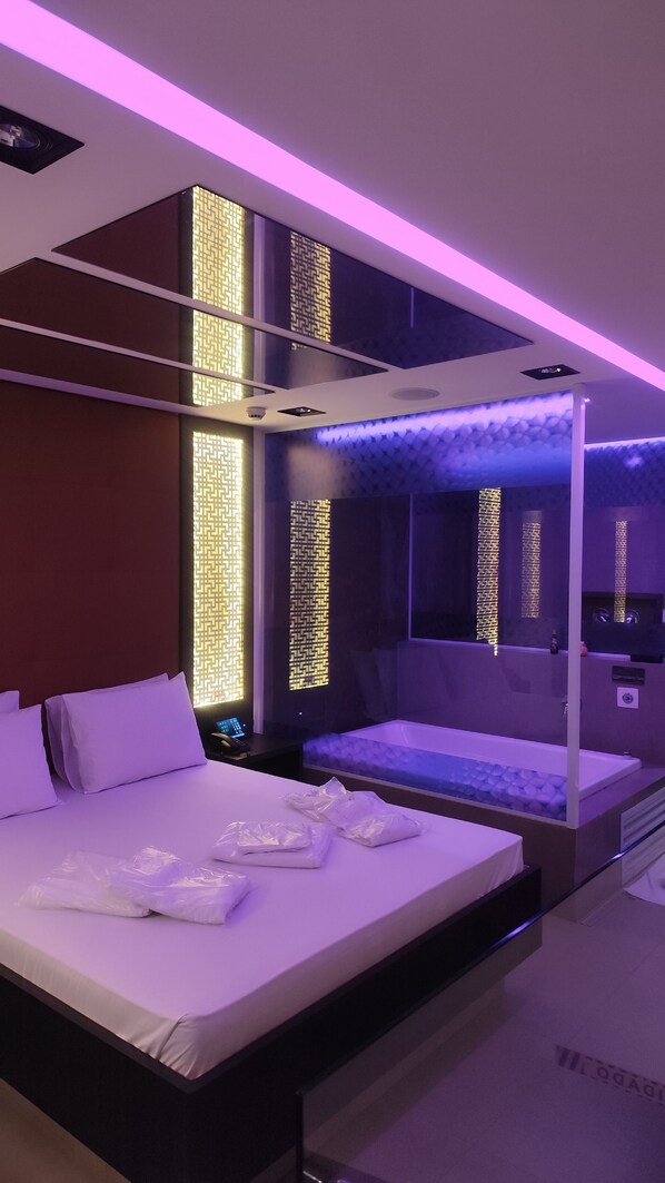 Een moderne slaapkamer met een groot bed, een ingebouwde bank en een muur met een geometrisch patroon.