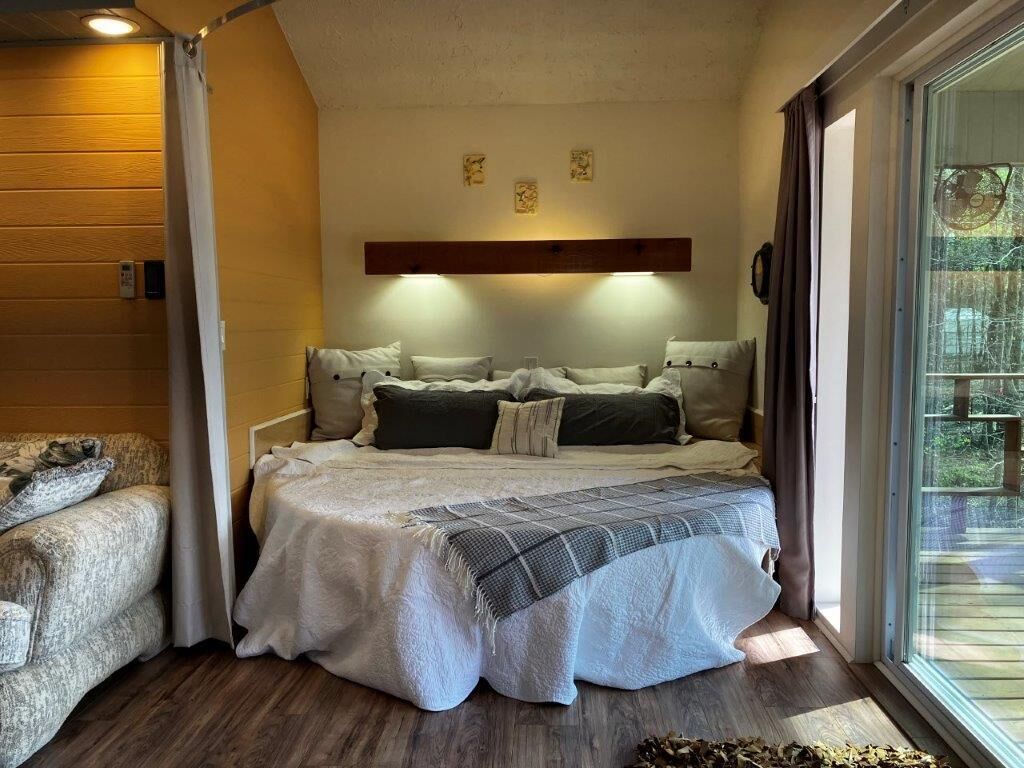 Un dormitorio acogedor con una cama, un sofá y un ventanal grande.