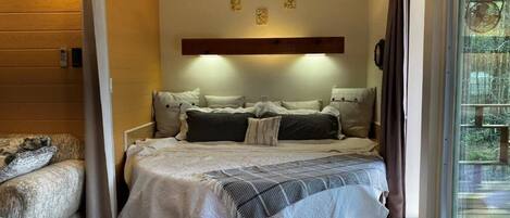 Un dormitorio acogedor con una cama, un sofá y un ventanal grande.