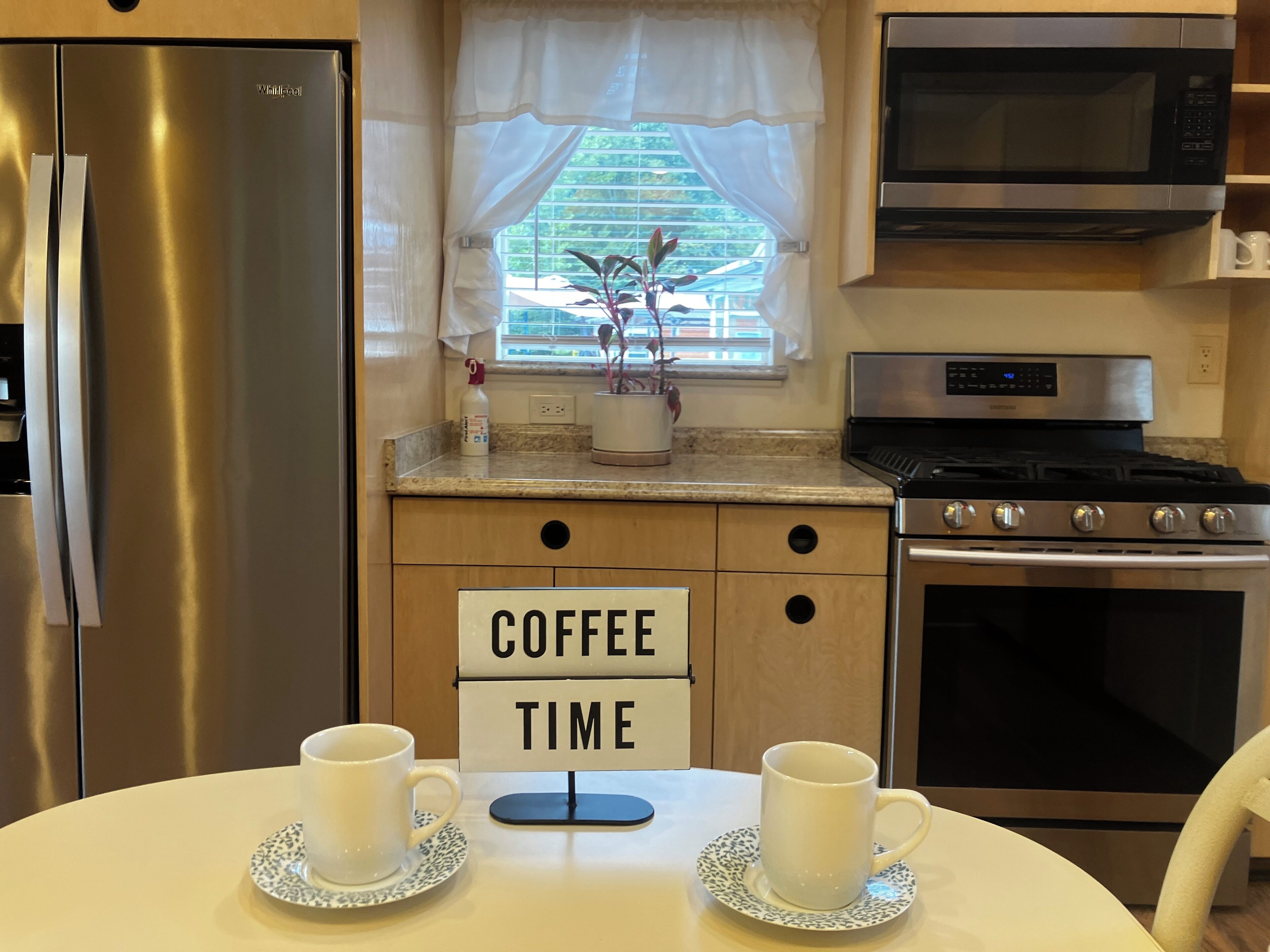 Una cucina con frigorifero in acciaio inossidabile, forno a microonde, forno e un cartello con la scritta 'caffè' sul bancone.