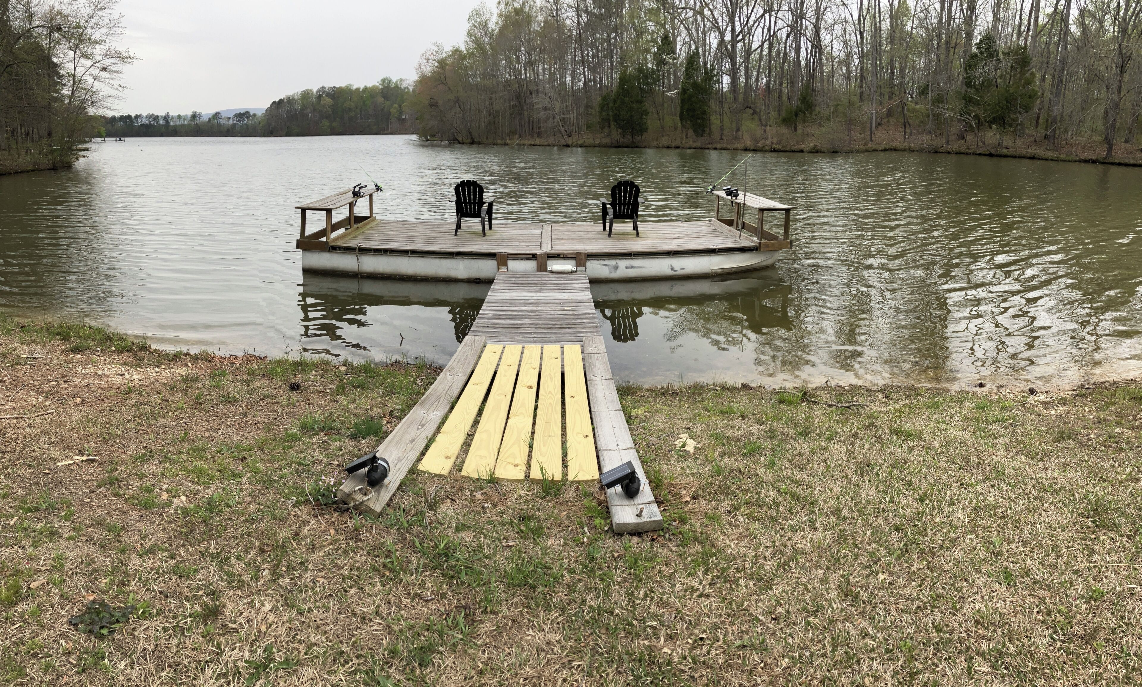 Une jetée en bois s’étendant sur un lac paisible, entourée d’arbres.