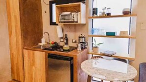 A compact kitchen with wooden cabinets, a built-in microwave, and a small dining table.