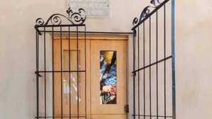 A wooden door with a metal gate, a small window with a view, and a sign above the door.