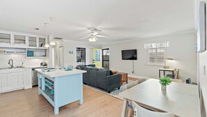 A modern kitchen with white cabinets, a blue island, and a dining area with a table and chairs.