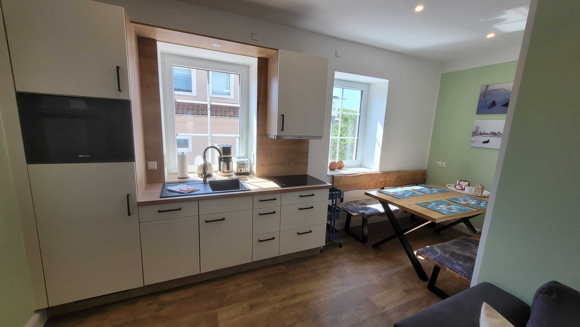 Cocina compacta con lavabo, estufa y comedor con mesa y sillas.