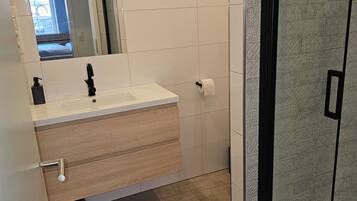 Ein modernes Badezimmer mit Waschbecken, Spiegel und Fliesen mit Muster.