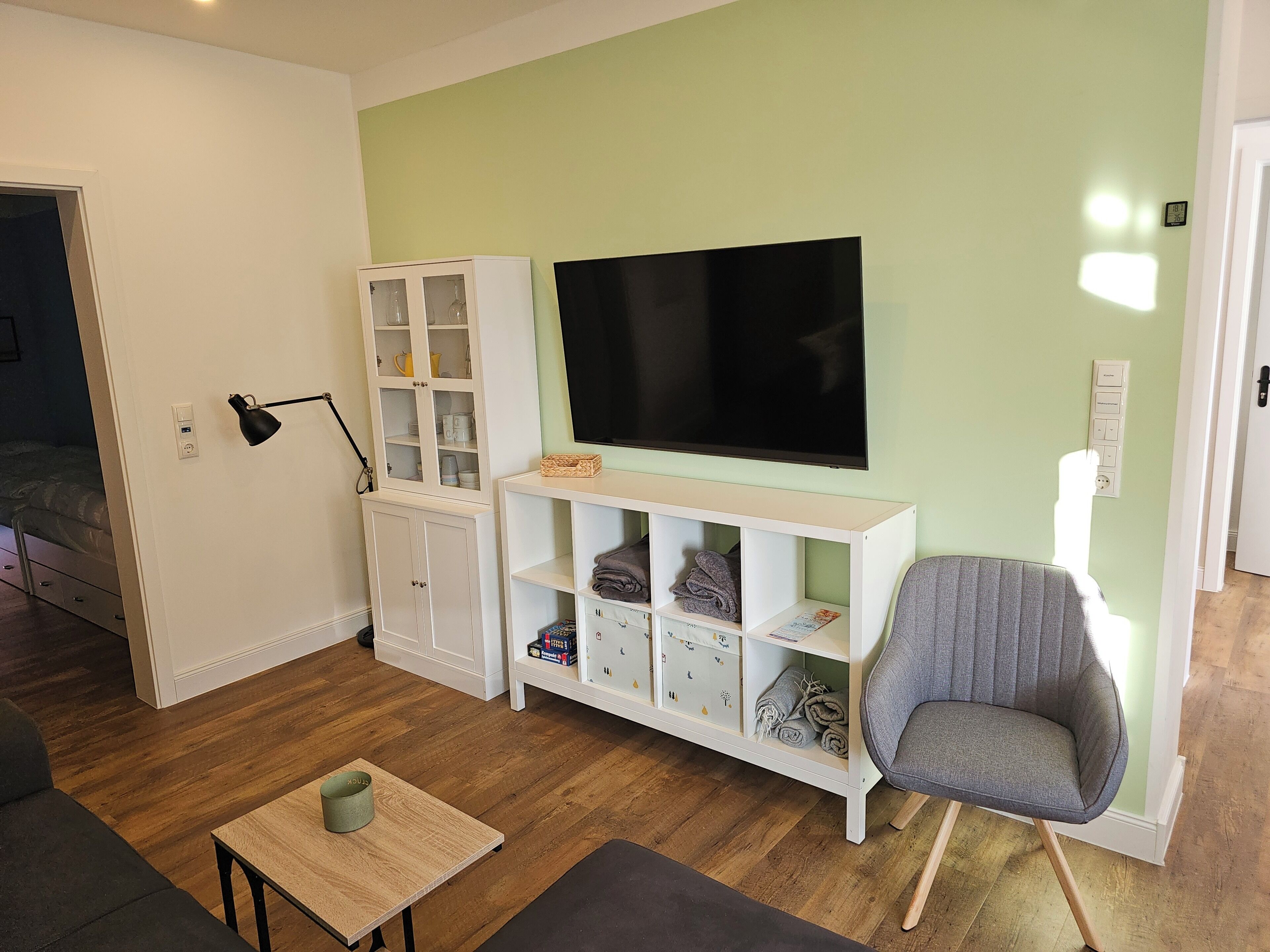 A living room with a TV, a cabinet, a chair, and a small table.