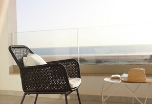 A balcony with a wicker chair and a small table with a straw hat and an open book. - Comfortable seafront apartment with terrace (Agadir)