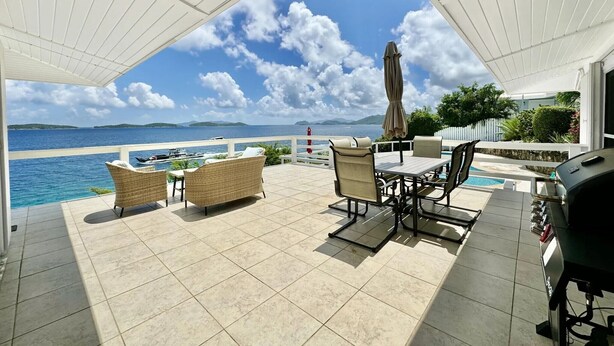 A covered outdoor patio with tiled flooring, wicker furniture, a grill, and a view of the sea and distant islands. - Waterfront,Private home&pool,Breathtaking Views,Great Location. Enjoy paradise! (St Thomas)