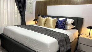 A modern hotel room with a large bed, a bedside table, and an air conditioning unit on the wall. - Duke Residence (Ibadan)
