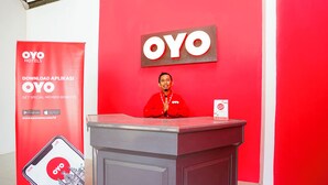 A person standing behind a podium with a red OYO Hotels sign in the background. - Hotel O Mojoanyar Near Terminal Bis Mojokerto (Mojokerto)